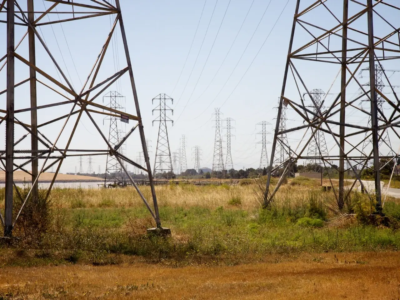 In this image we can see mobile towers and wires. At the bottom there is grass. In the background...