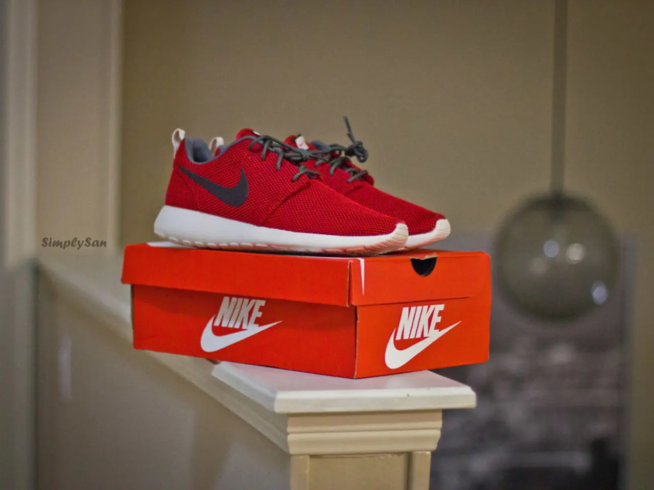 In the center of the image we can see red shoes and a box placed on the wall.