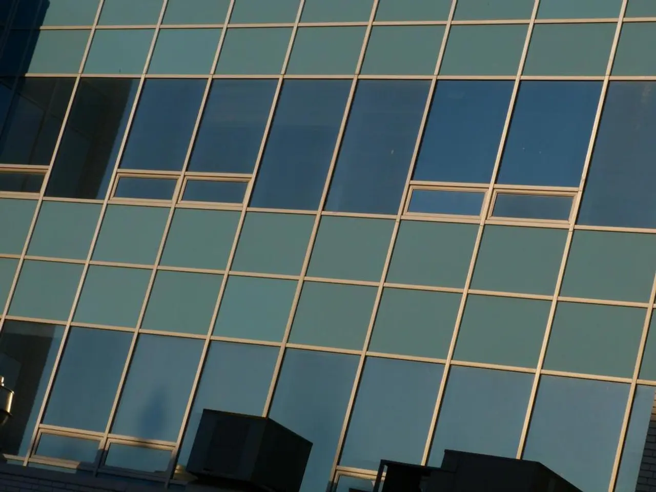 In this image we can see the glasses of a building. We can see the reflection of a building on the...