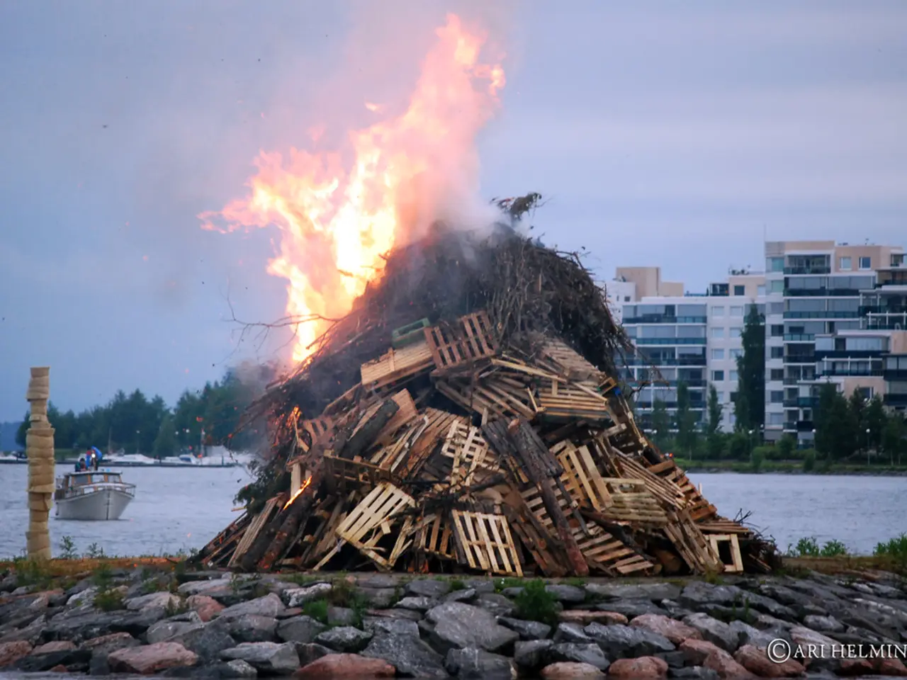 In this picture there are wooden objects burning with the fire. At the bottom, there are stones. In...