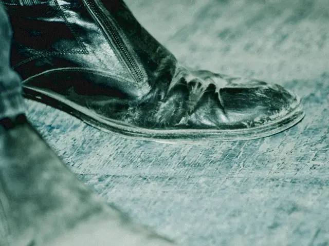 In this picture we can see a pair of shoes on the floor. On the left side of the image, there is a...