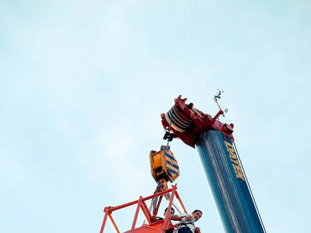 In the center of the image we can see a crane and two persons are standing in the crane bucket. In...
