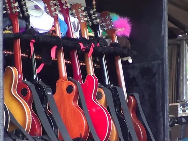 In this image we can see seven guitars of different color.