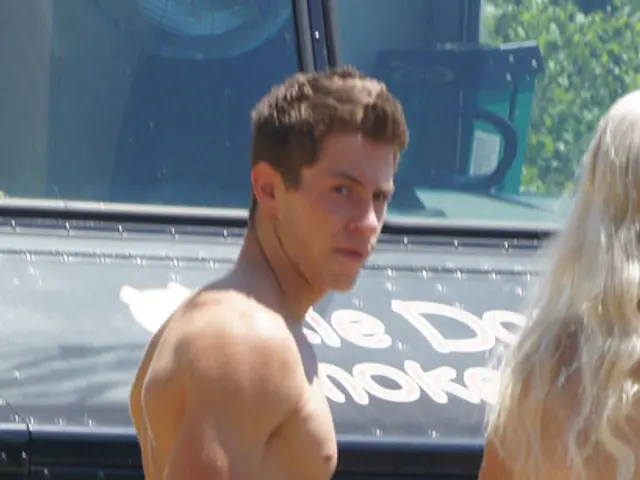 In this image there is a man and a woman standing. At the bottom of the image there is some text,...