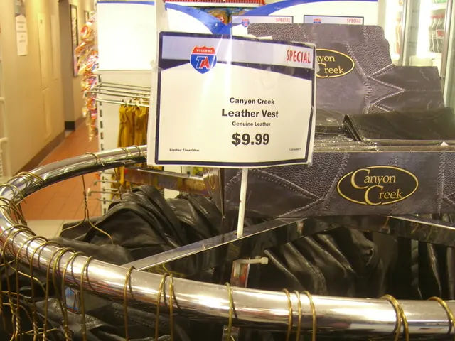 In this image I can see few black colored vests are hanged to the metal rods. I can see the white...